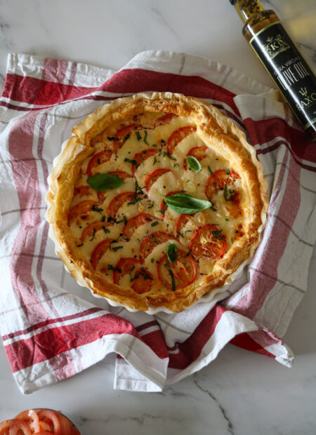 Tarte tomate mozzarella et poulet dorée au four sur une table avec huile d'olive de Paxos