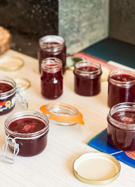 Confiture de raisin Muscat maison dans un pot en verre, avec des raisins frais en arrière-plan.