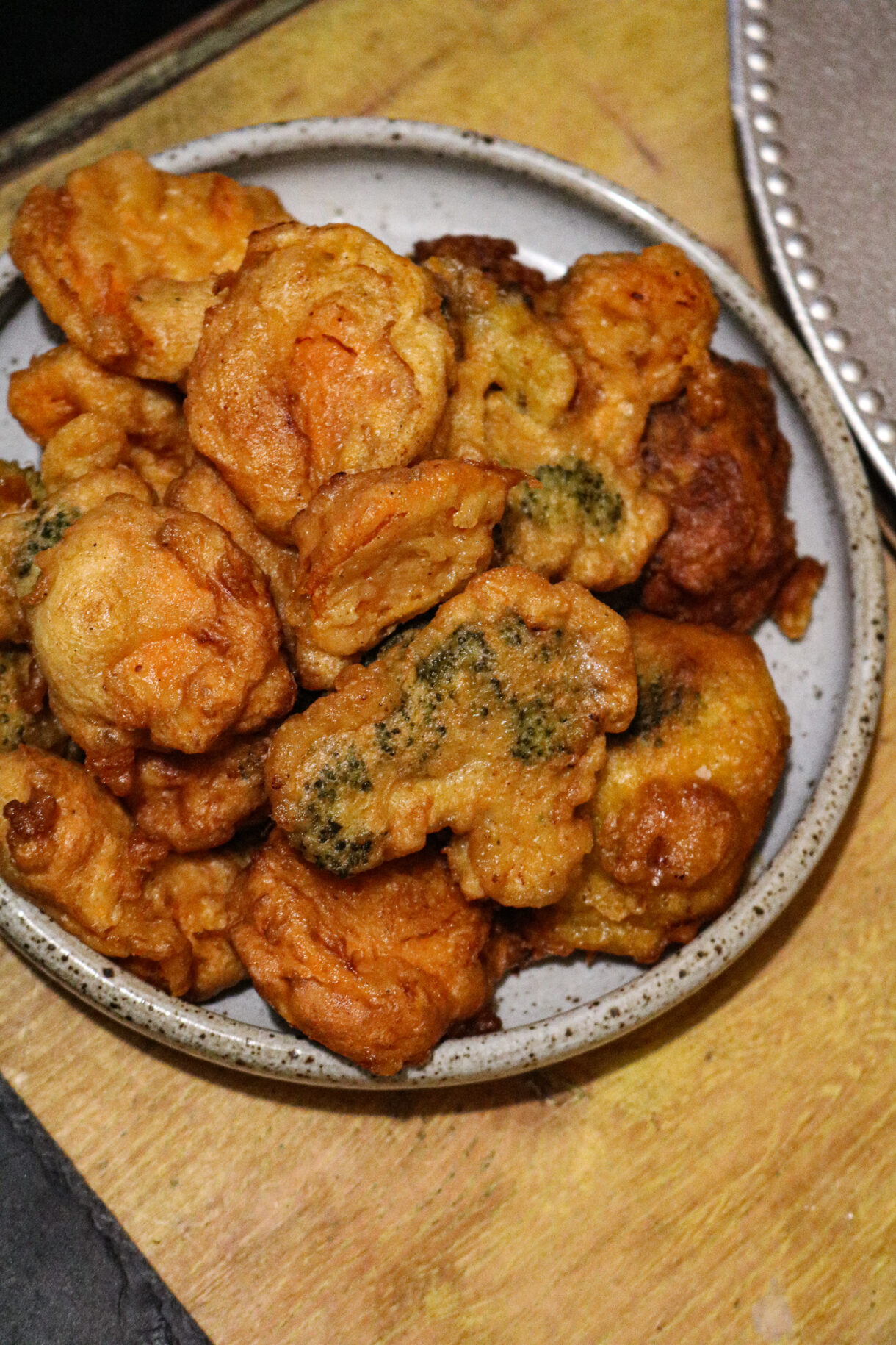 Beignets dorés de chou-fleur, brocolis et patate douce dans une assiette en céramique