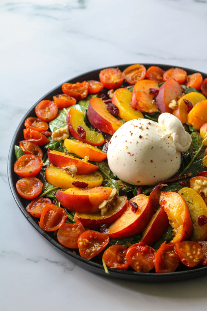 plat avec pêches rôties burrata, pousses épinards et tomates confites