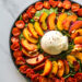 Vue d'ensemble d'une salade avec pêches rôties burrata, pousses épinards et tomates confites
