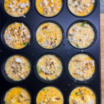 Moule de 12 muffins remplis d’une préparation avec un appareil de quiche.