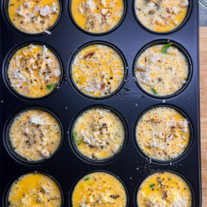 Moule de 12 muffins remplis d’une préparation avec un appareil de quiche.