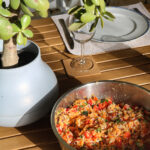 Table avec le bol contenant les ingrédients pour salade de lentilles corail : riz, légumes, citron et huile d’olive
