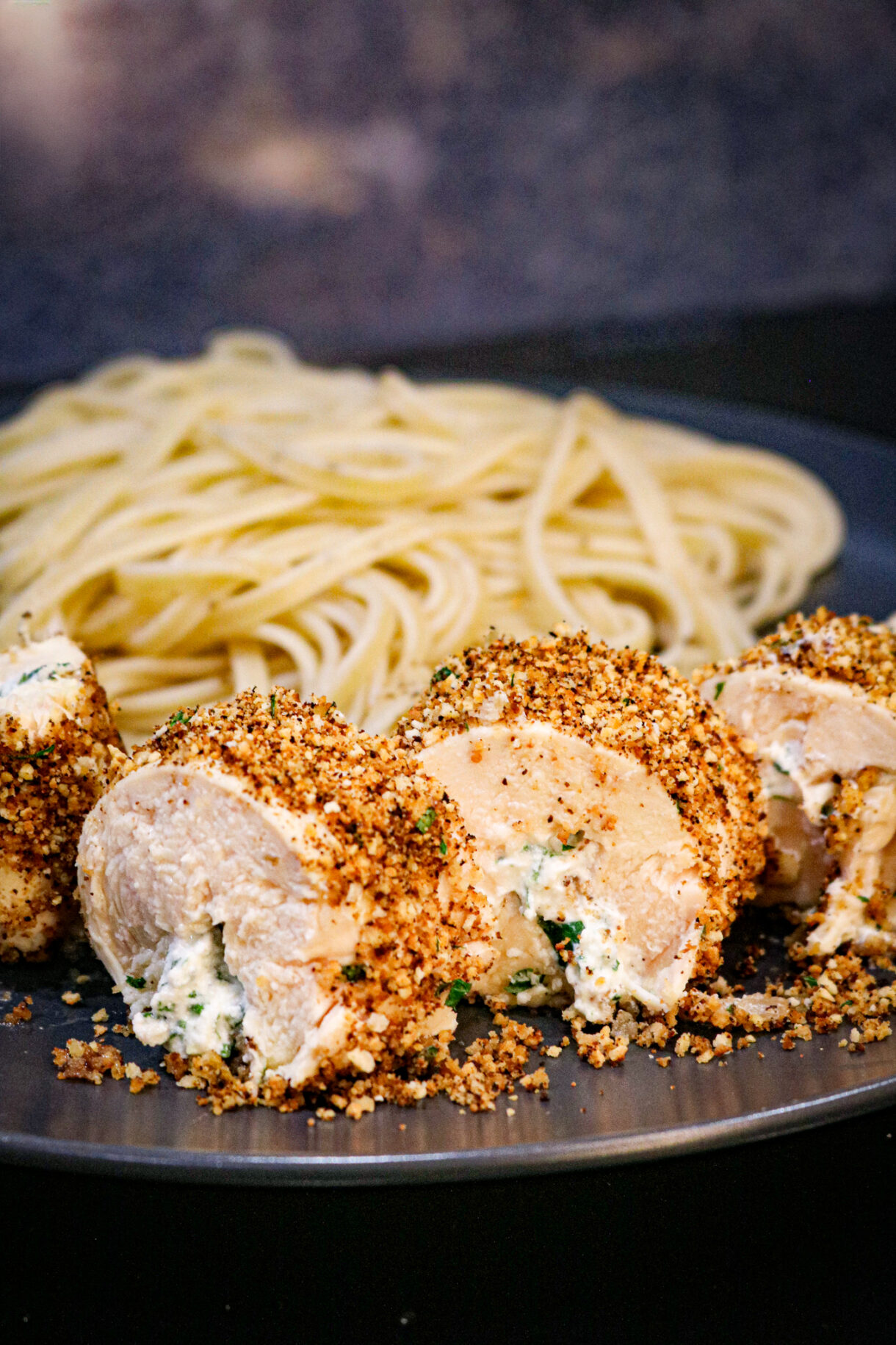Zoom sur la ballotine de poulet farcie avec des pâtes au citron en arrière-plan.