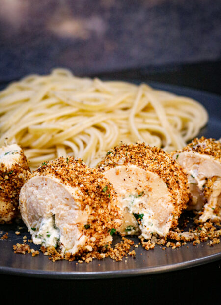 Zoom sur la ballotine de poulet farcie avec des pâtes au citron en arrière-plan.