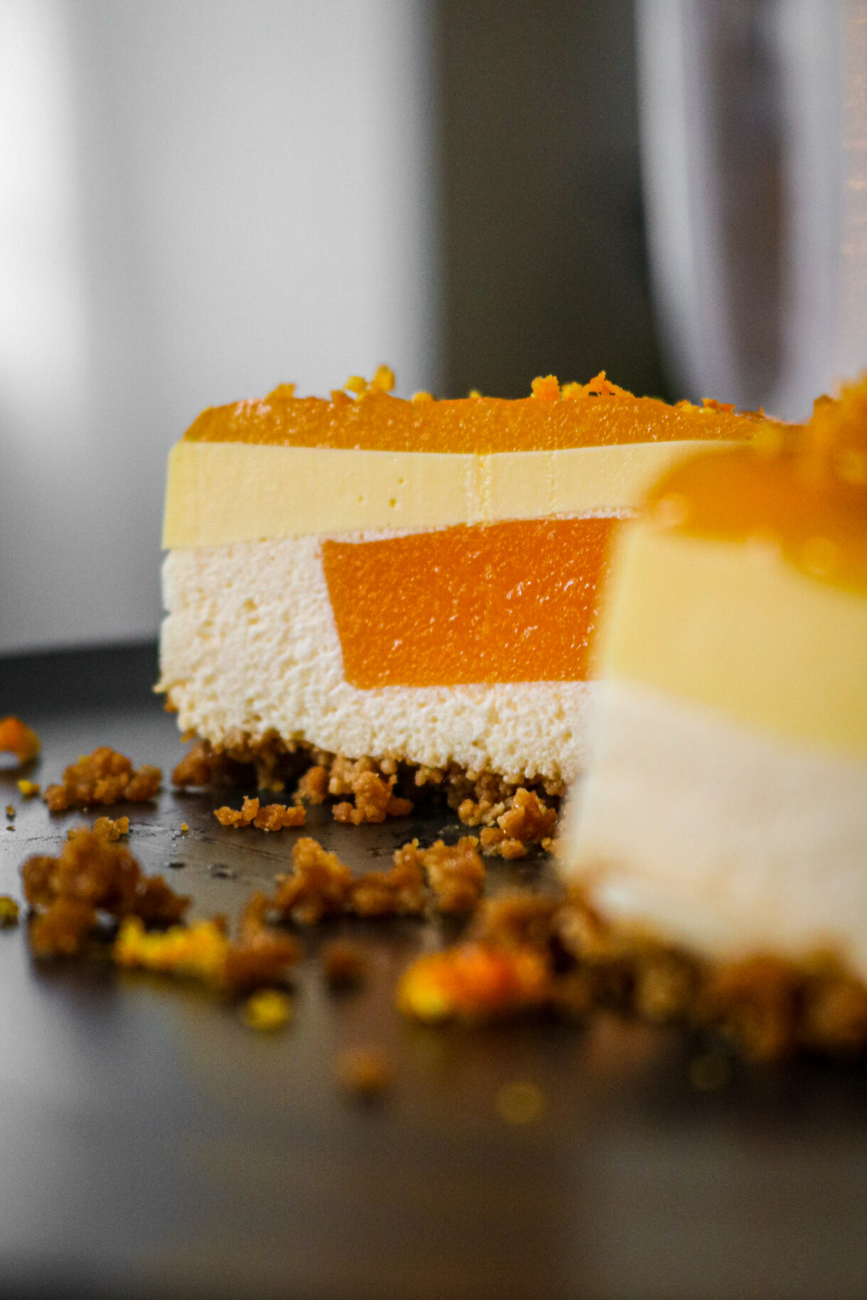 Gros plan d’un entremet à la clémentine avec son glaçage brillant, zestes de clémentine pour finition.