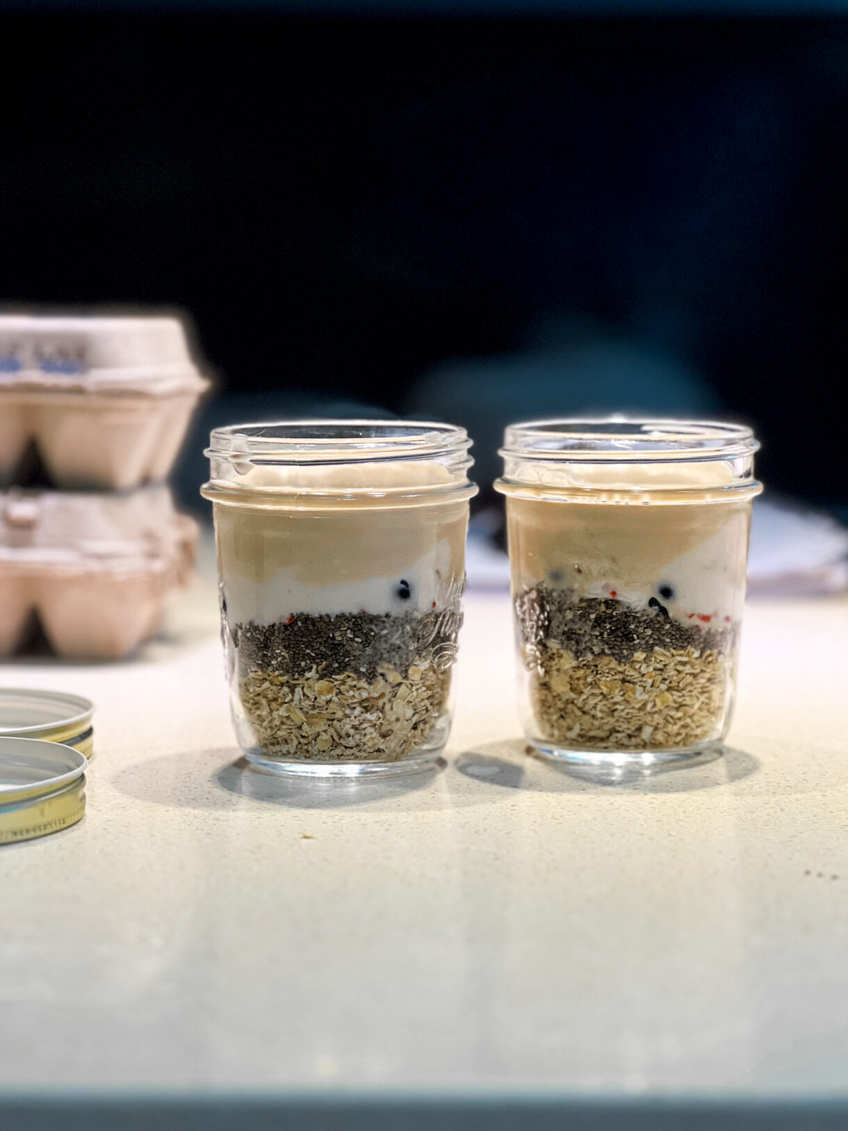 Overnight oats dans un bocal, garni de fruits frais et de granola, prêt à être dégusté.