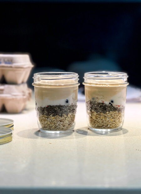 Overnight oats dans un bocal, garni de fruits frais et de granola, prêt à être dégusté.