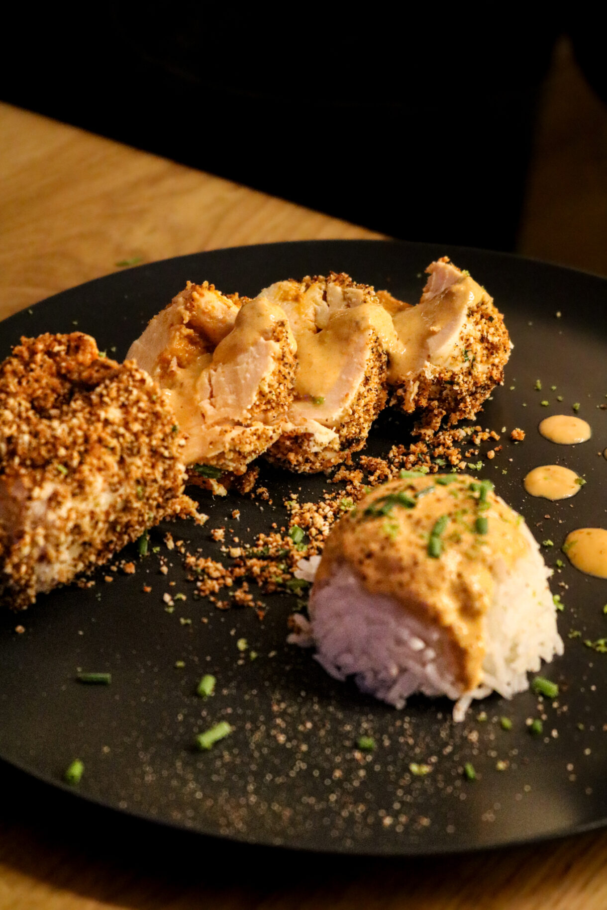 Assiette dressée avec une ballotine de poulet coupées et du riz recouvert de la sauce