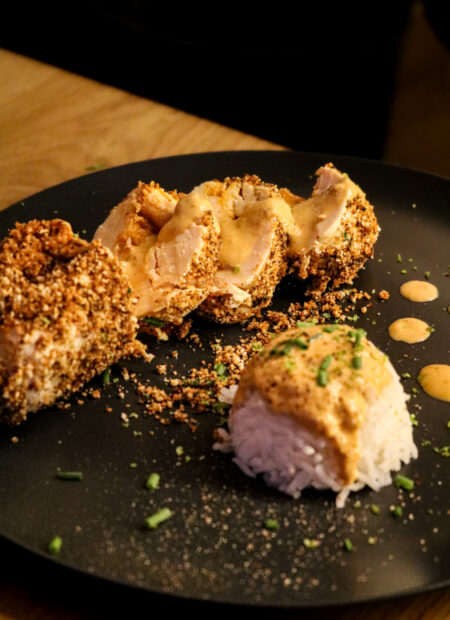 Assiette dressée avec une ballotine de poulet coupées et du riz recouvert de la sauce