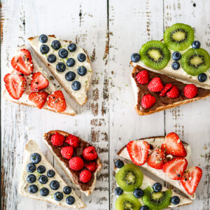 4 toasts sucrées garnies avec des fruits, sur une base de fromage frais
