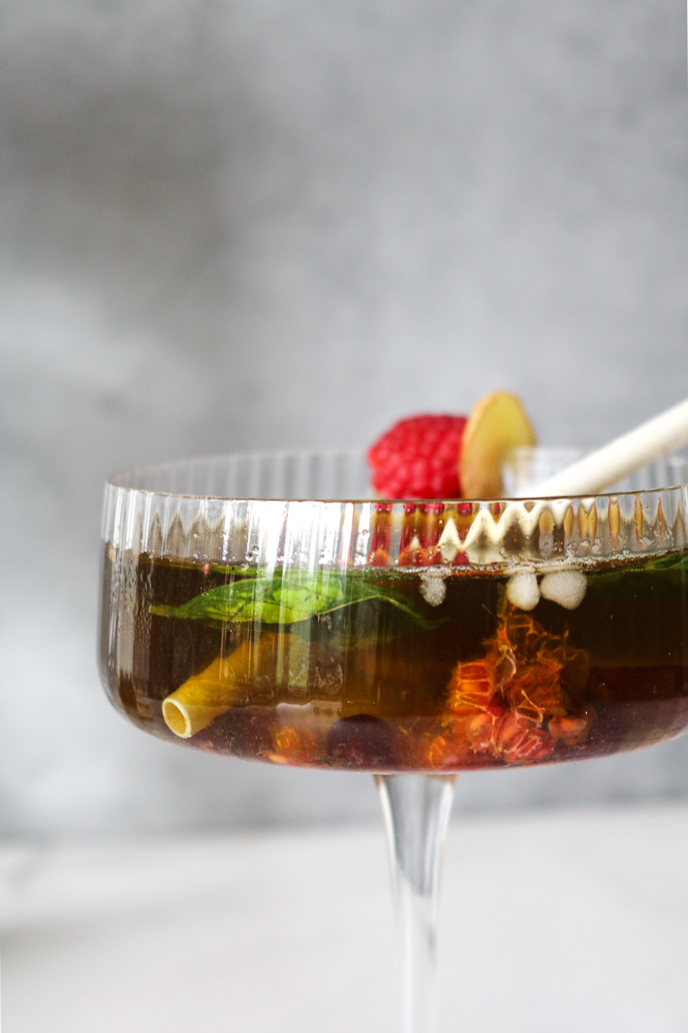 Gros plan sur un mocktail peche framboise au the vert infuse a froid et basilic