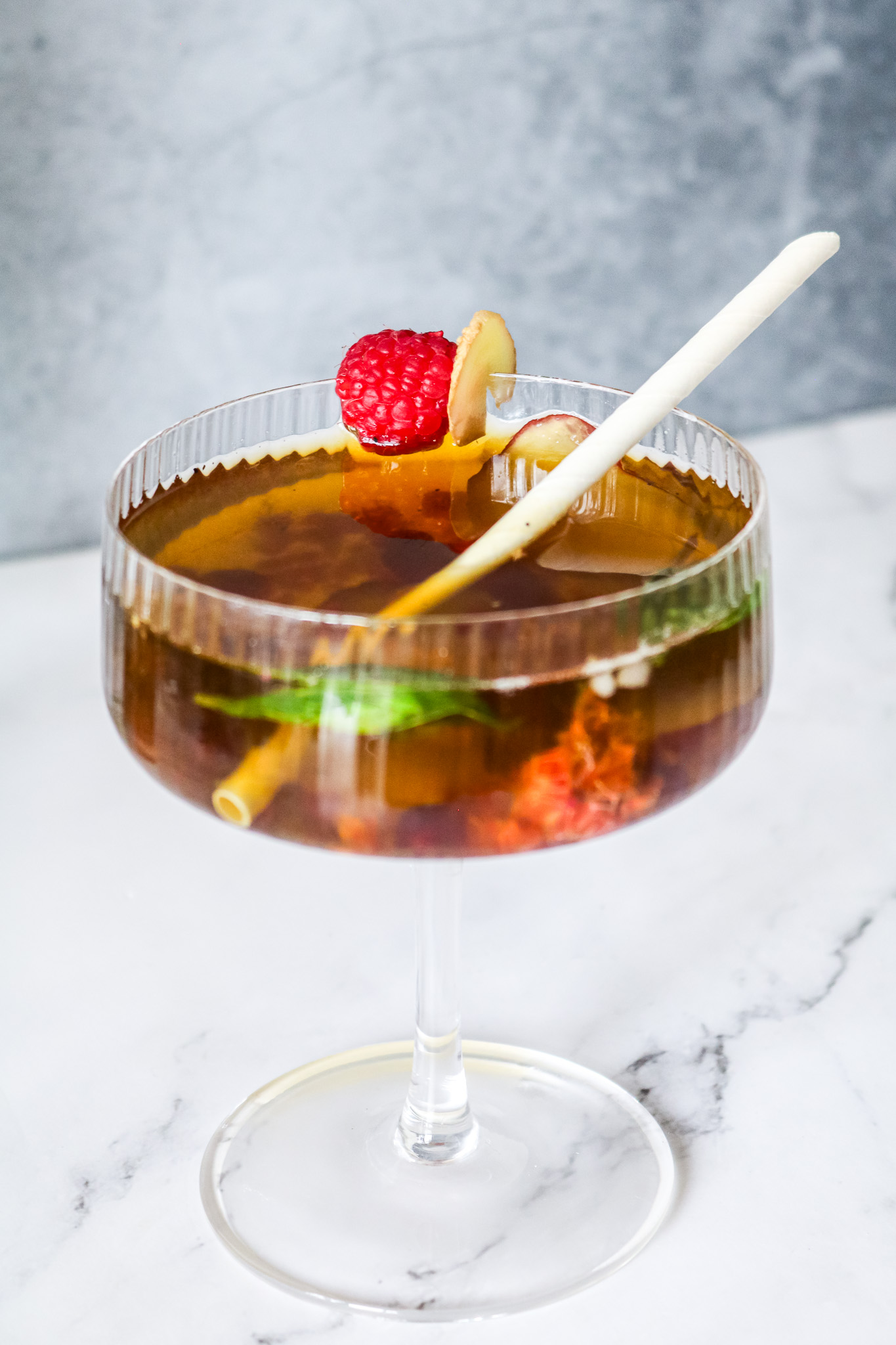 Mocktail de thé vert infusé à froid pêche et framboise dans un verre sur pied