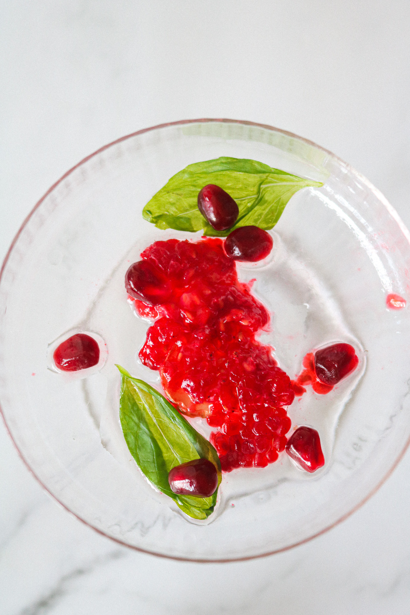 Framboises fraîches graines de grenade et feuilles de basilic au fond d'un verre de mocktail