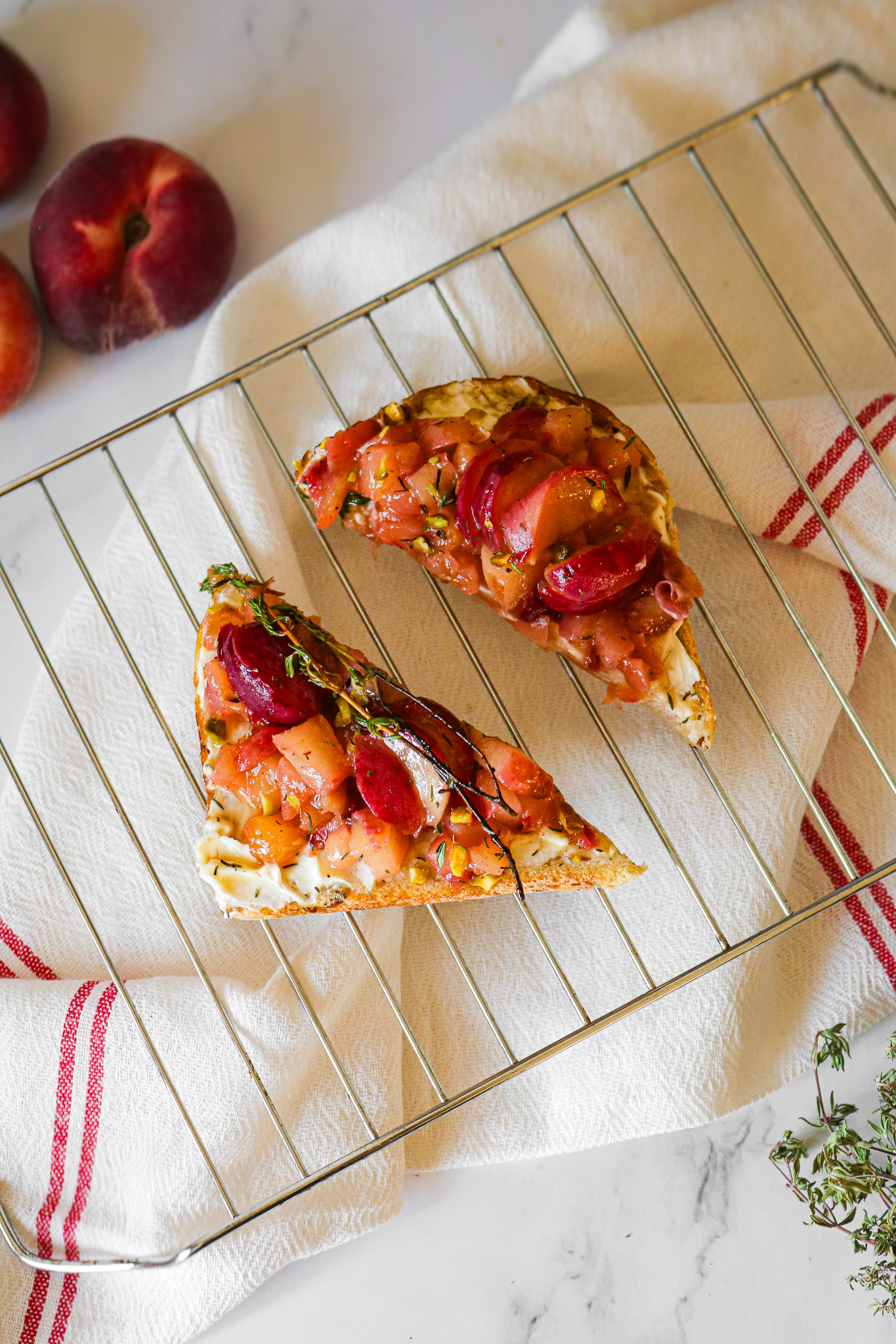 Deux toasts peche et Philadelphia au miel disposes sur une grille avec du thym frais