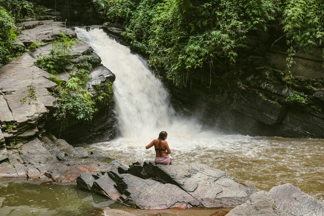 Adeline Bernard assise sur un rocher face à une cascade à Chiang Mai