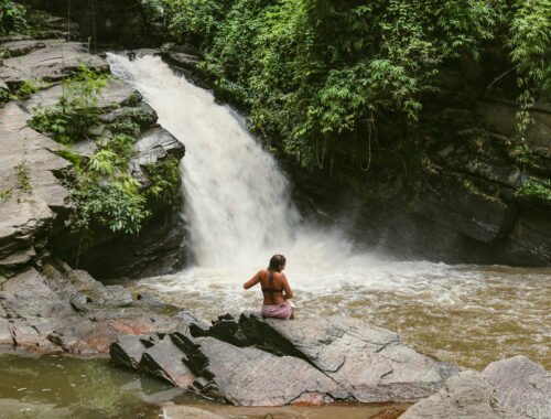 Adeline Bernard assise sur un rocher face à une cascade à Chiang Mai