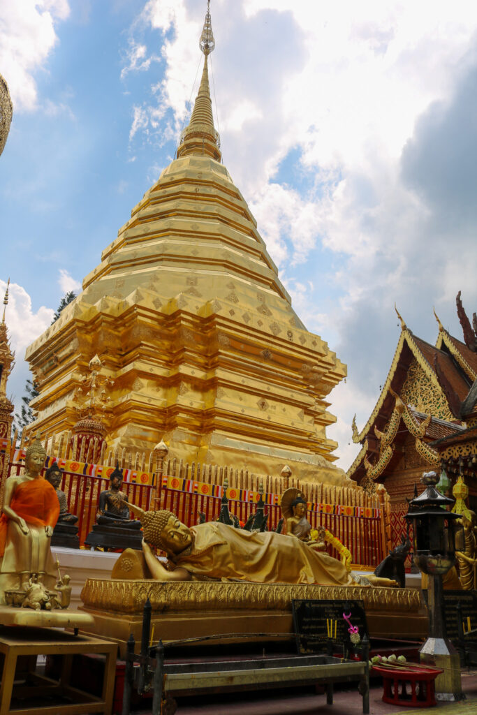 Statue de Bouddha allongé devant le clocher doré du Wat Phra That Doi Suthep