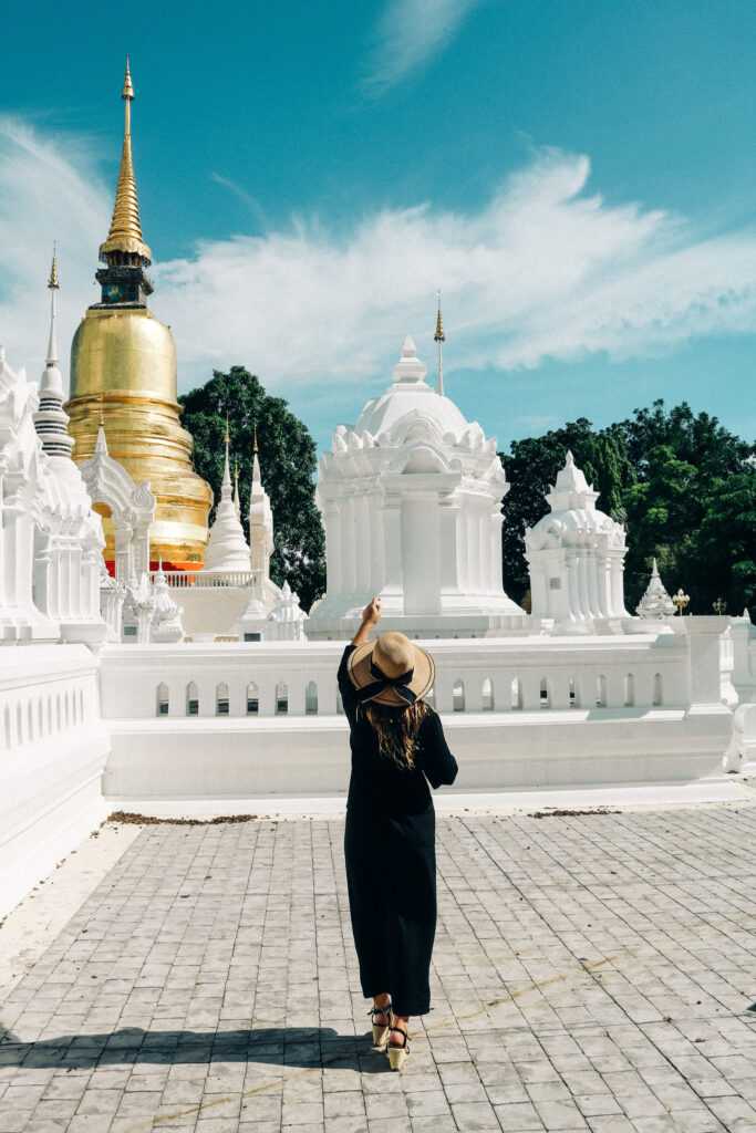 Adeline Bernard devant un temple blanc orné d’un clocher doré à Chiang Mai