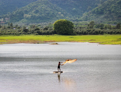 Pêcheur qui lance son filet sur un lac