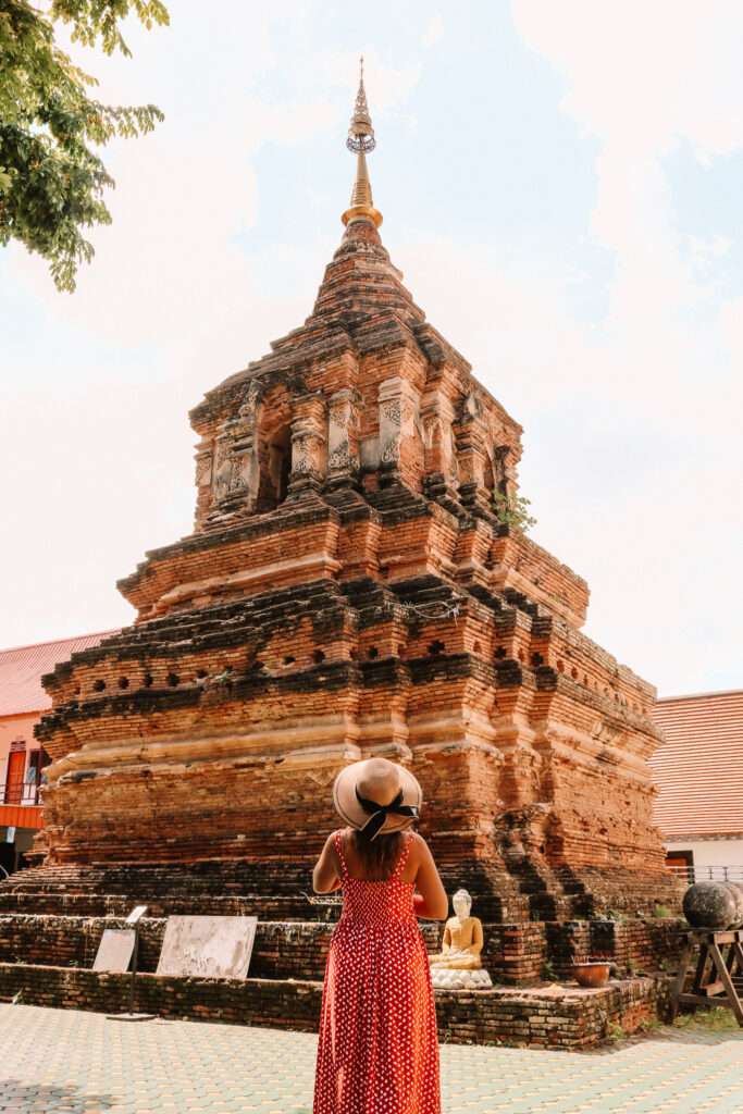 Adeline Bernard devant un temple ancien en briques rouges, architecture traditionnelle de Chiang Mai
